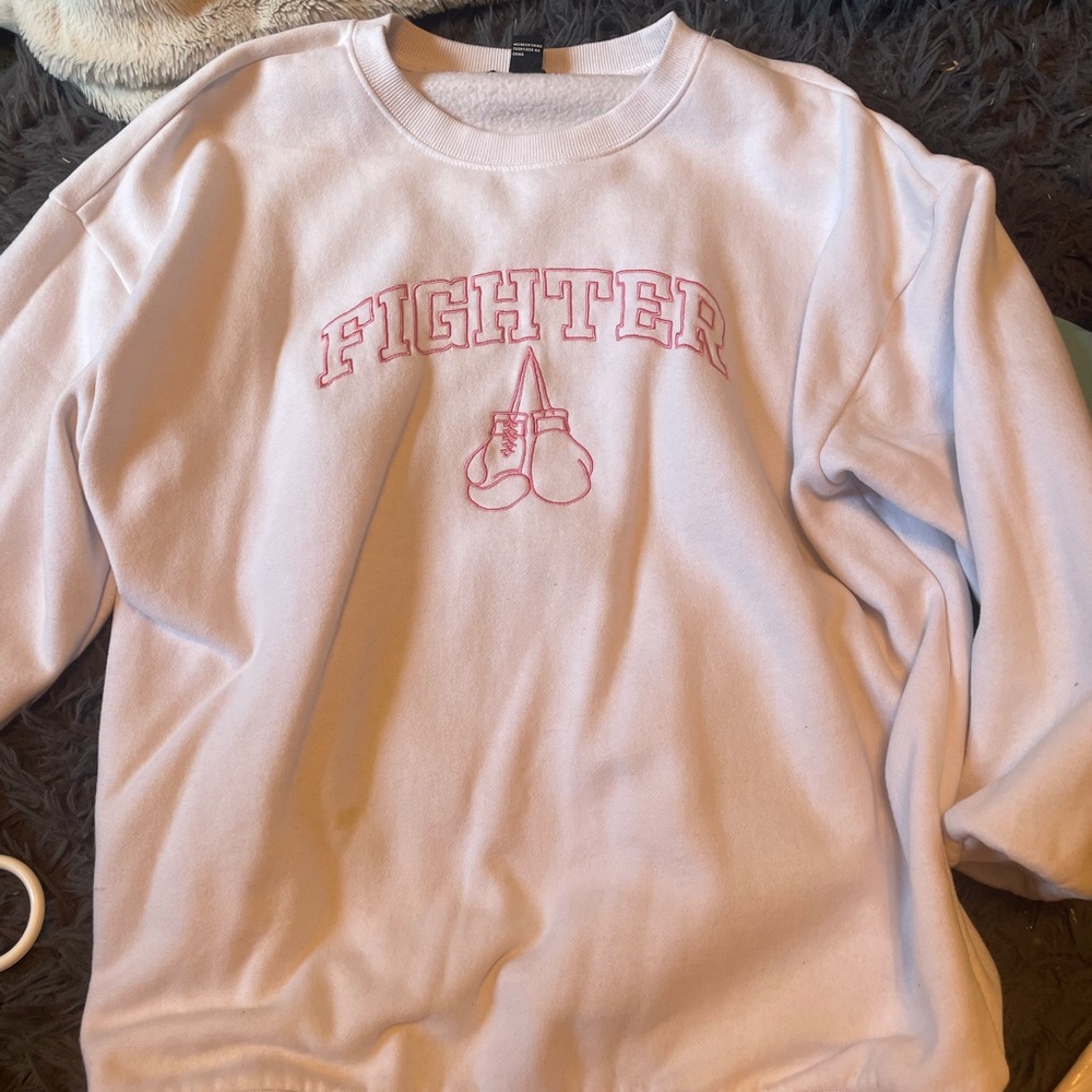 white crew neck with pink writing that says fighter, small.